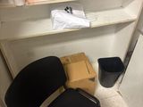 a black chair sitting in front of a shelf with a coffee pot on it