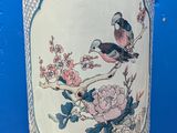 a vase with a bird on it sitting on a table