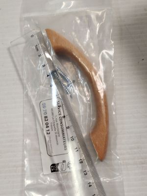 un objet en bois dans un sac en plastique, à côté d'une règle