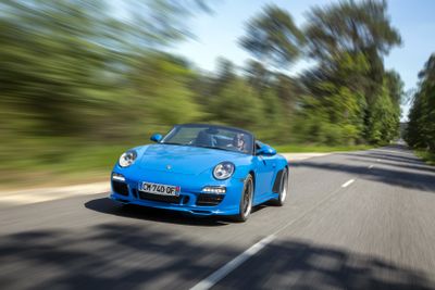 the blue sports car is driving down the road in motion