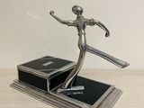 statue of a woman holding a tennis racquet on top of a wooden table