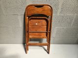 a wooden chair with a black seat next to a gray wall