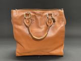 a brown leather handbag on a black background