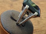 a ring with a green stone on top of a wooden stand