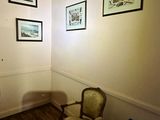 a chair in the corner of a room with pictures on the wall