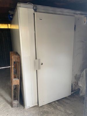 un réfrigérateur blanc dans un garage, avec une chaise en bois