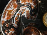 many plates and bowls on the table with a clock in the background