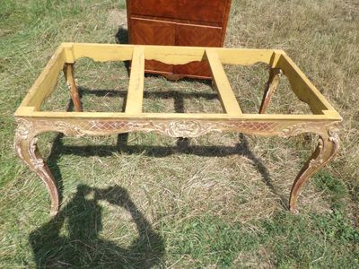 une table en bois avec un plateau en verre, posée dans l'herbe