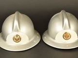pair of white fireman ' s helmets on a black background