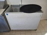 une casserole noire posée sur un congélateur blanc