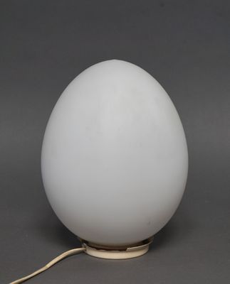 une lampe en forme d'œuf, dotée d'un abat-jour en verre blanc et d'un pied doré