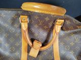 a brown and tan louis vuitton bag with a wooden handle
