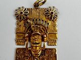 a close up of a gold pendant on a white surface