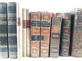 several old books are lined up in a row on a shelf