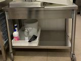 une table de travail en acier inoxydable équipée d'un évier et d'une poubelle