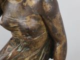 an antique bronze statue of a woman sitting on a rock
