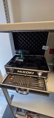 une boîte à outils contenant des outils, posée sur une étagère dans une pièce