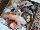 une boîte posée par terre, avec une poupée à l'intérieur