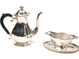 a silver tea pot and saucer on a saucer