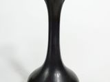 a black vase that is sitting on a white surface