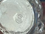 a glass vase with a silver lid sitting on a table