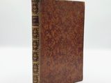 an old book with a brown cover sitting on top of a white surface