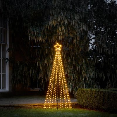 lighted christmas tree in front of a house in the rain