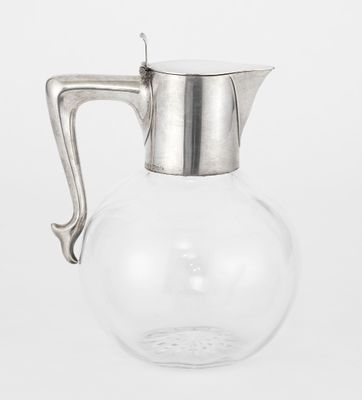 a clear glass pitcher with a metal handle sitting on a white surface