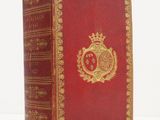un livre rouge aux bords dorés, surmonté d'une couronne