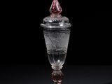 an old glass with a red top sitting on top of a table