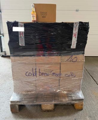une palette remplie de cartons sur laquelle est accrochée une pancarte indiquant « café infusé à froid »