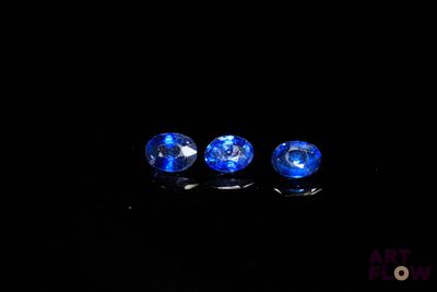 trois perles de verre bleues posées sur une surface noire