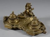 an antique brass inkwell with a woman sitting on top of it