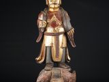 une statue en bois représentant un homme tenant une épée et debout sur un rocher