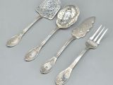 quatre cuillères en argent et une fourchette sont alignées sur une table