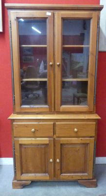 a wooden china cabinet with glass doors and a red wall
