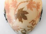 a wall mounted vase with a leaf design on it