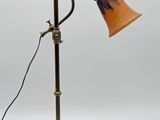 an antique brass table lamp with an orange shade on a white background