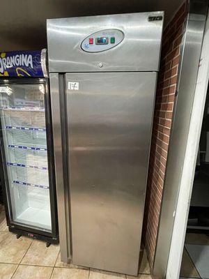 a silver refrigerator in the middle of a tiled floor