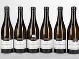six bottles of wine are lined up in a row on a white surface