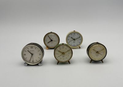 quatre petites horloges posées les unes sur les autres sur une surface blanche