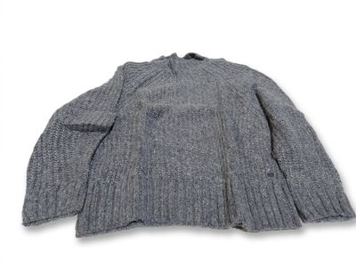Le pull est gris et a des manches longues.