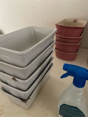 a stack of dishes sitting on a counter next to a bottle of cleaner