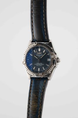 a close up of a watch with a blue dial on a black strap