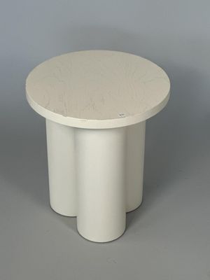 une image représentant une table blanche au plateau rond posée sur une surface grise