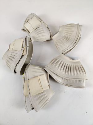 trois paires de chaussures blanches ornées de nœuds, posées sur une surface blanche