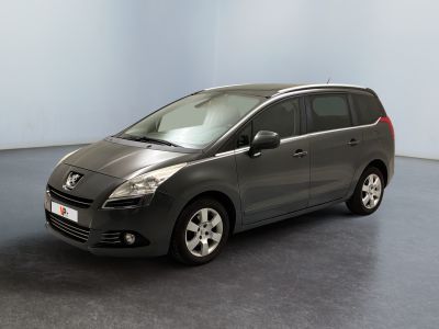 La voiture grise est garée dans une grande pièce au sol noir.