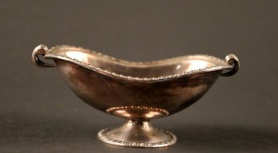 un petit bol en argent avec une anse sur une table