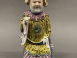 a figurine of a woman in a yellow dress holding a bag