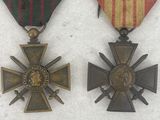 two medals are shown on a white surface with a red, yellow, and green ribbon